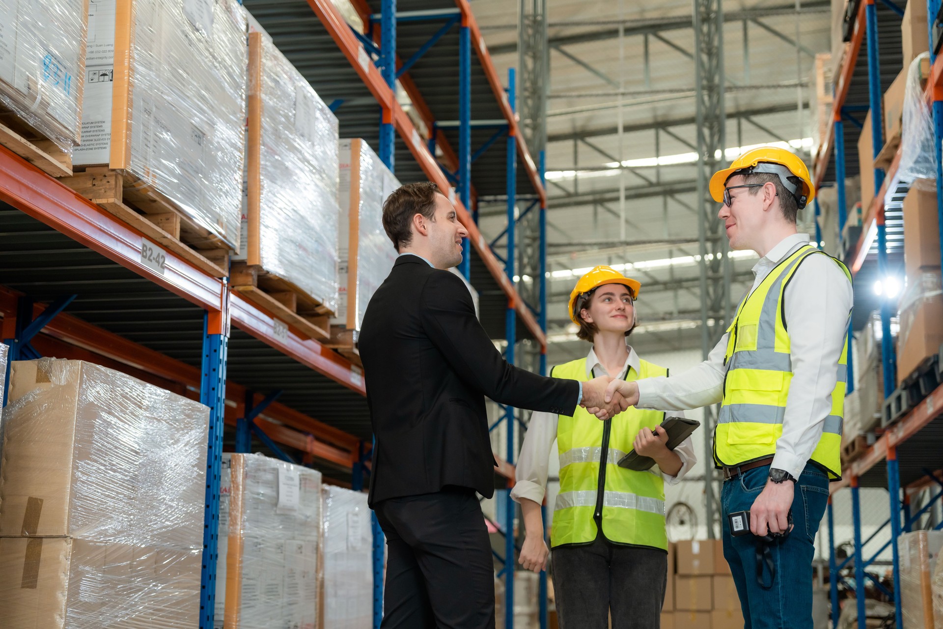 Successfully completed work. A man and a woman in a business suit shake hands and conclude a deal for the warehouse business. A businesswoman and a businessman at work successfully make a deal