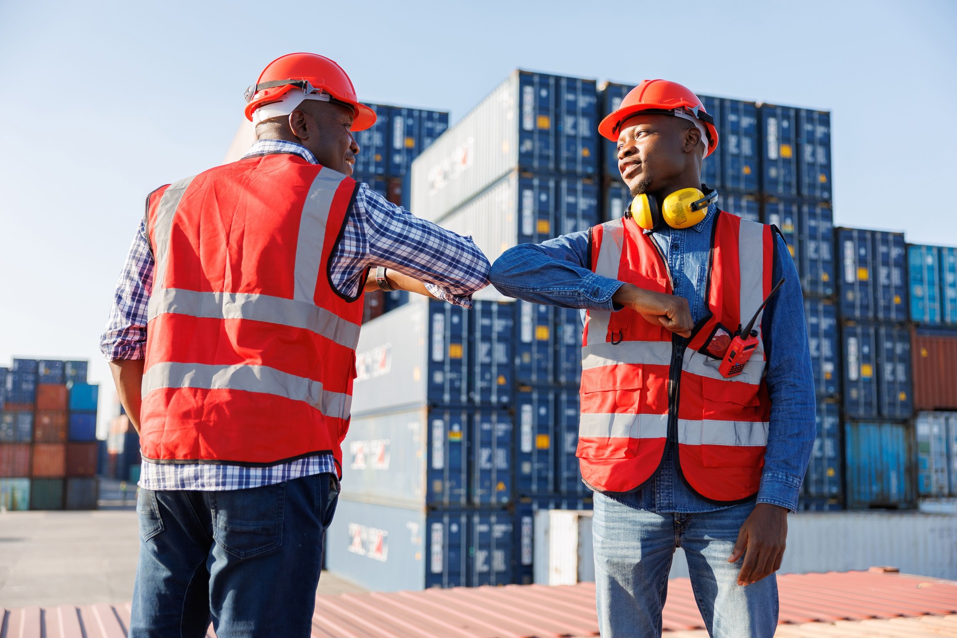 African factory workers or engineer greeting with elbow bumps in containers warehouse storage