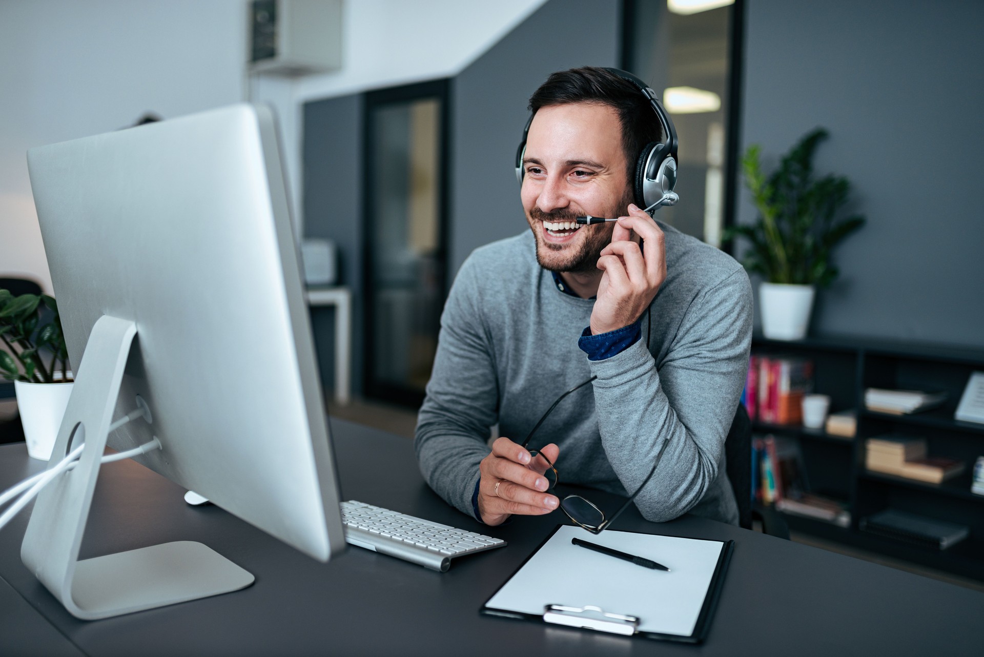 Happy young customer support operator talking to his satisfied client.